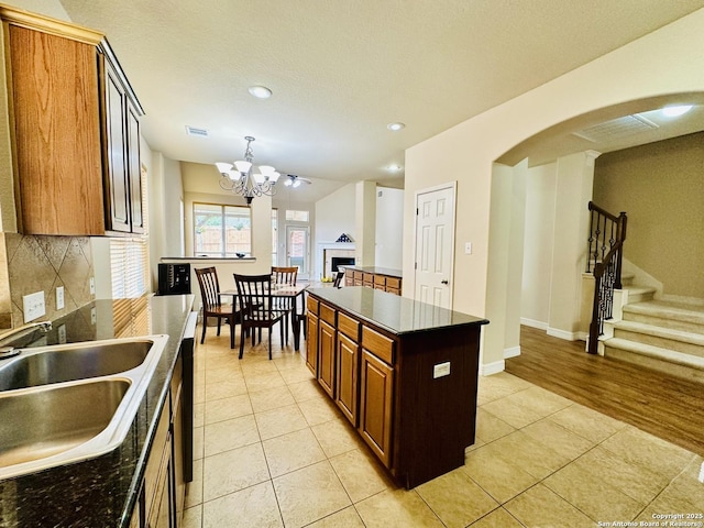 kitchen featuring sink, backsplash, a center island, a notable chandelier, and light tile patterned flooring