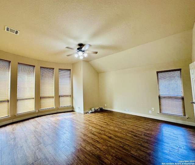 spare room featuring hardwood / wood-style flooring, ceiling fan, vaulted ceiling, and a textured ceiling