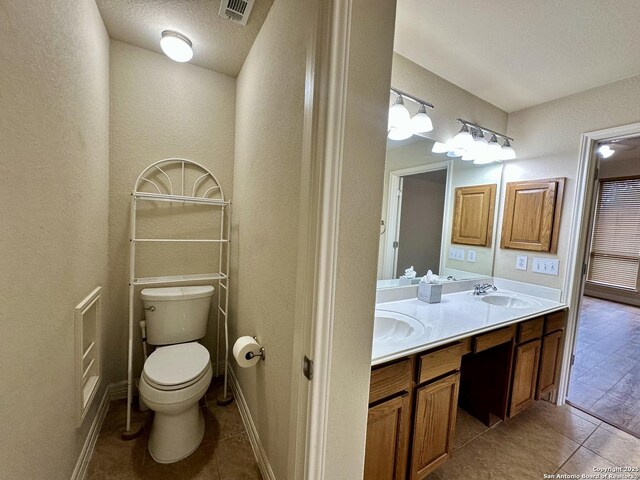 bathroom featuring tile patterned floors, toilet, vanity, and a textured ceiling