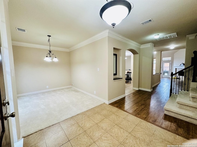 tiled spare room featuring ornamental molding and a chandelier