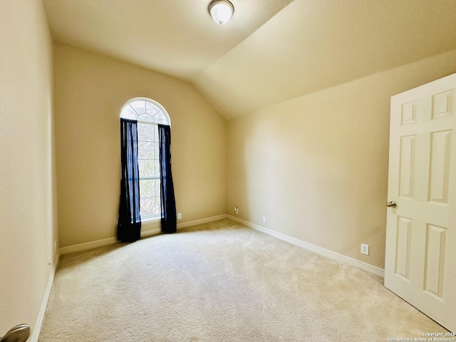 carpeted spare room with lofted ceiling