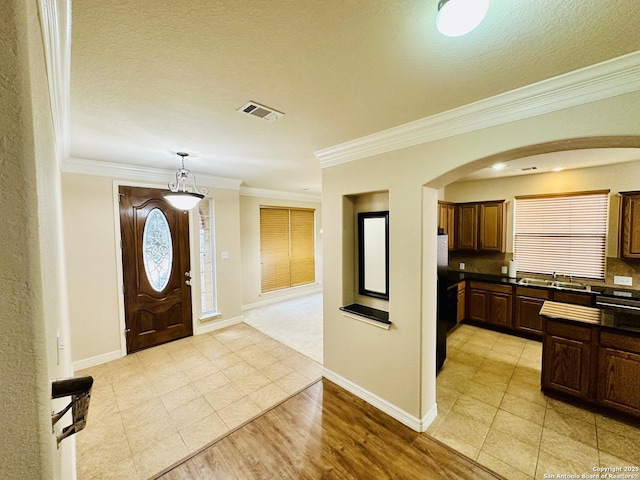 foyer featuring crown molding, light hardwood / wood-style flooring, and a textured ceiling