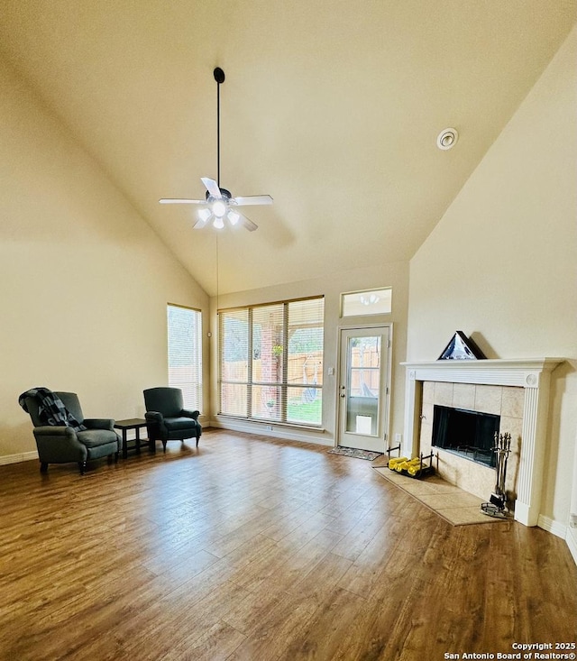 sitting room featuring ceiling fan, high vaulted ceiling, a tiled fireplace, and hardwood / wood-style floors