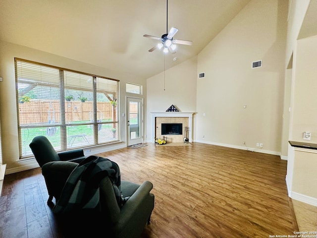 living room with hardwood / wood-style flooring, high vaulted ceiling, a premium fireplace, and ceiling fan