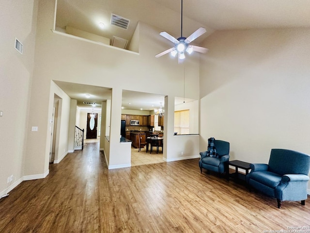 sitting room featuring ceiling fan with notable chandelier, vaulted ceiling, and light wood-type flooring