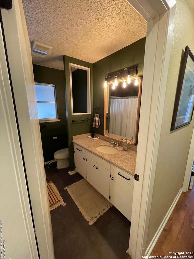 bathroom with vanity, hardwood / wood-style floors, toilet, and a textured ceiling