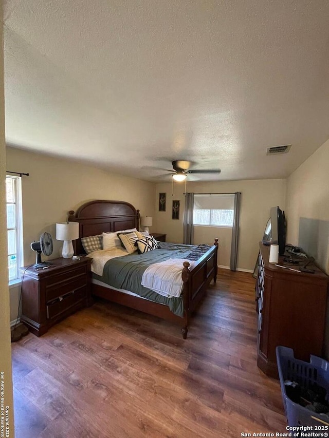 bedroom featuring ceiling fan, dark wood-type flooring, and a textured ceiling