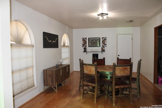 dining room with wood-type flooring and a textured ceiling