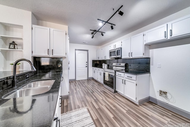 kitchen with dark stone countertops, appliances with stainless steel finishes, sink, and white cabinets