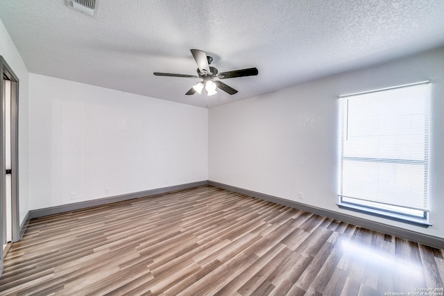 unfurnished room with ceiling fan, a textured ceiling, and light wood-type flooring