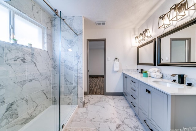 bathroom featuring an enclosed shower, vanity, and a textured ceiling