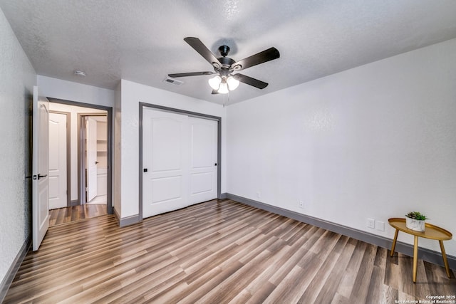 unfurnished bedroom featuring ceiling fan, light hardwood / wood-style floors, a closet, and a textured ceiling