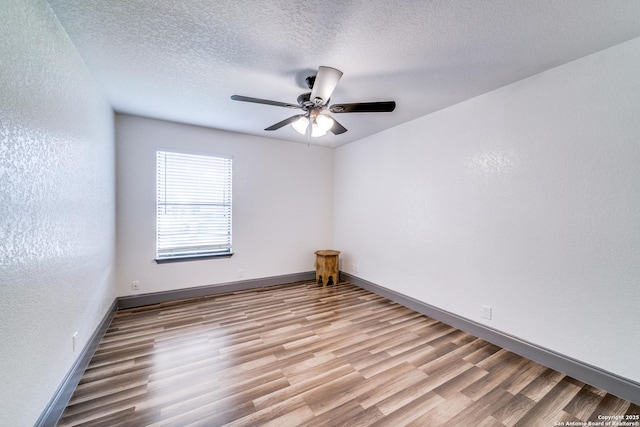 empty room featuring ceiling fan, a textured ceiling, and light wood-type flooring