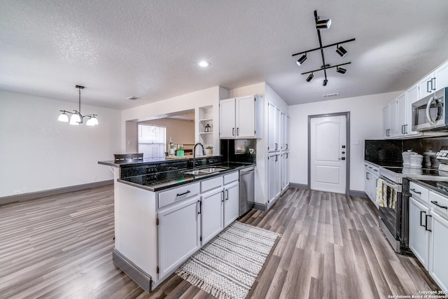 kitchen featuring sink, appliances with stainless steel finishes, hanging light fixtures, white cabinets, and kitchen peninsula