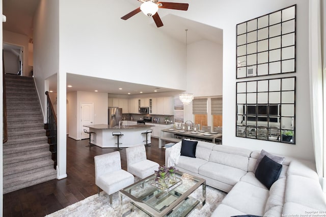 living room featuring ceiling fan with notable chandelier, high vaulted ceiling, and dark hardwood / wood-style floors