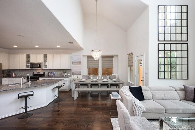 living room with high vaulted ceiling, dark hardwood / wood-style floors, sink, and a chandelier