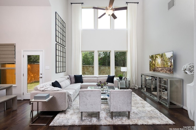 living room with a high ceiling, dark hardwood / wood-style floors, and ceiling fan