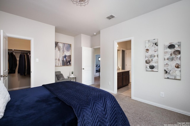 bedroom with connected bathroom, a spacious closet, and light colored carpet