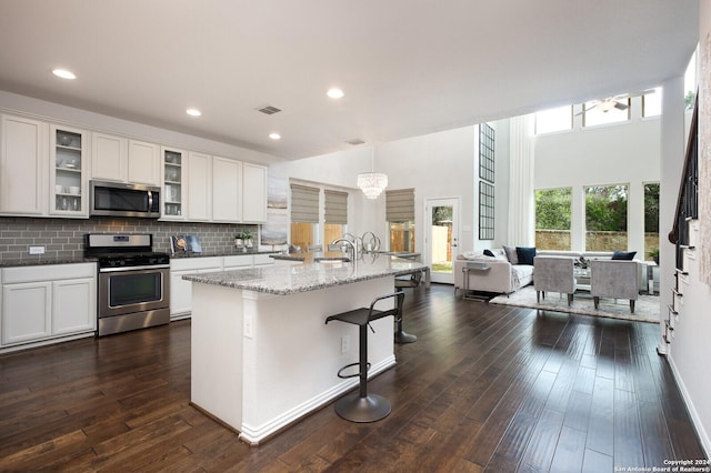 kitchen with stainless steel appliances, a breakfast bar area, a center island with sink, and white cabinets