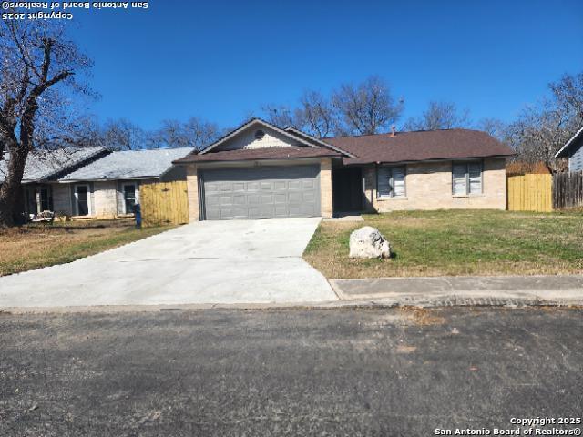 ranch-style house with concrete driveway, a front lawn, an attached garage, and fence