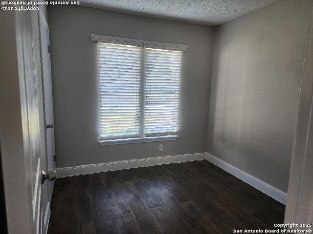 spare room with dark wood-type flooring and a textured ceiling