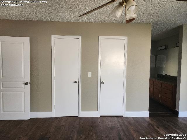 unfurnished bedroom with a textured ceiling, dark wood-style flooring, and baseboards