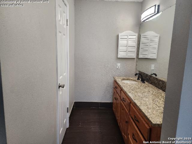 bathroom with a textured wall, wood finished floors, and vanity