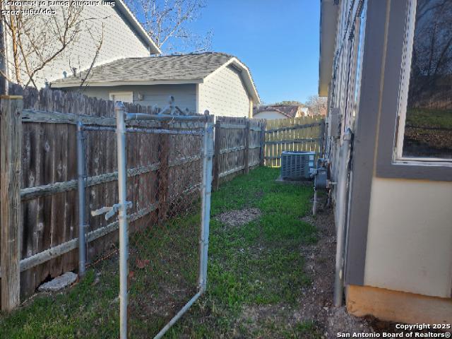 view of yard featuring central AC unit and fence