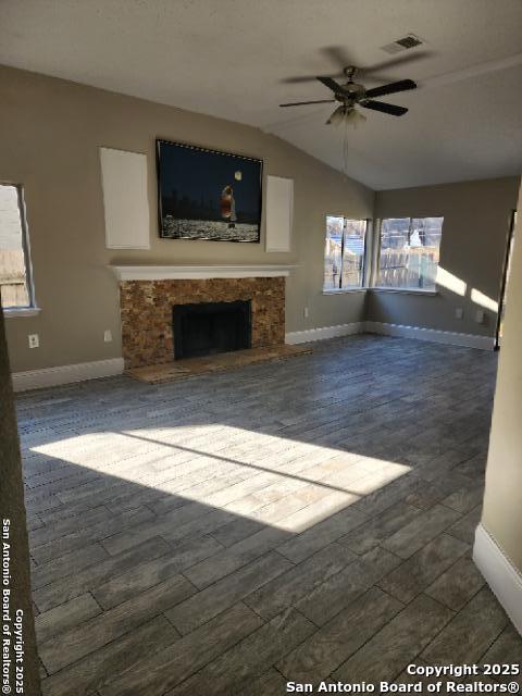 unfurnished living room with baseboards, visible vents, dark wood finished floors, lofted ceiling, and a fireplace