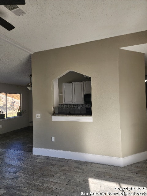 room details with a textured ceiling, wood finished floors, visible vents, and baseboards