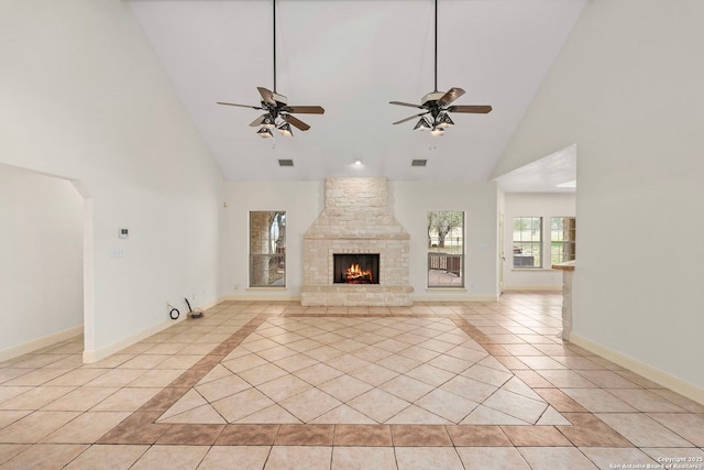 unfurnished living room with light tile patterned flooring, ceiling fan, a fireplace, and high vaulted ceiling