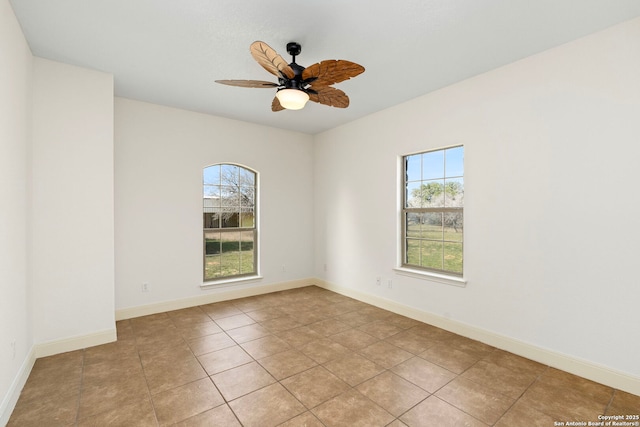 spare room with ceiling fan, a healthy amount of sunlight, and light tile patterned floors