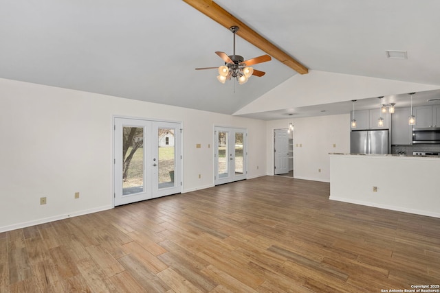 unfurnished living room featuring beamed ceiling, hardwood / wood-style floors, ceiling fan, and french doors