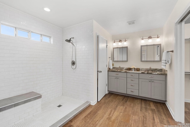 bathroom with tiled shower, wood-type flooring, and vanity