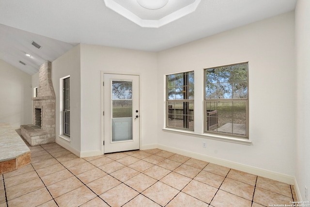 interior space featuring lofted ceiling, a large fireplace, and light tile patterned floors