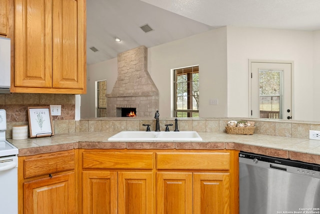 kitchen featuring sink, dishwasher, electric range, tasteful backsplash, and a stone fireplace