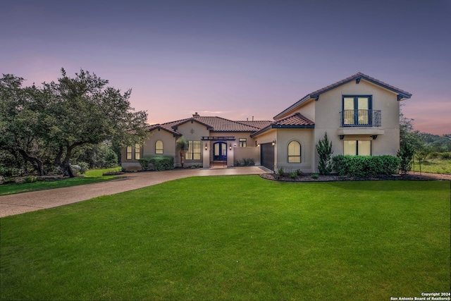 mediterranean / spanish home with a garage, a balcony, and a lawn