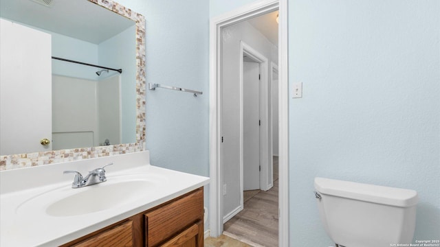 bathroom featuring vanity, toilet, hardwood / wood-style floors, and a shower