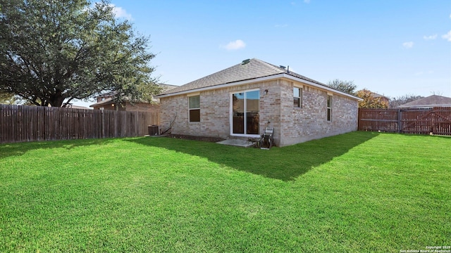 back of property with central AC unit and a yard