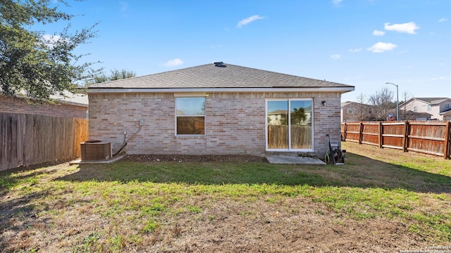 rear view of house featuring cooling unit and a lawn