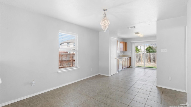 empty room with light tile patterned flooring and a chandelier