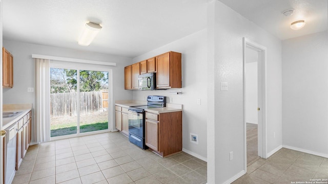 kitchen with sink, light tile patterned floors, and black appliances