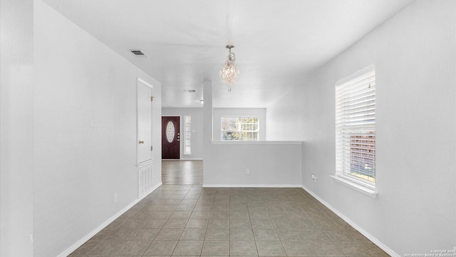 unfurnished room featuring a notable chandelier and dark tile patterned flooring