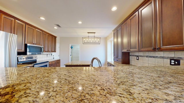 kitchen featuring sink, light stone counters, tasteful backsplash, hanging light fixtures, and appliances with stainless steel finishes