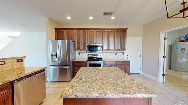 kitchen featuring light tile patterned flooring, stainless steel appliances, electric water heater, and a kitchen island