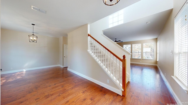 stairs featuring hardwood / wood-style floors and ceiling fan with notable chandelier