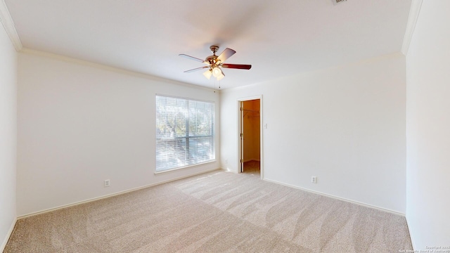 unfurnished room with crown molding, light colored carpet, and ceiling fan