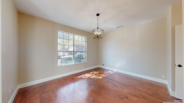 unfurnished room with wood-type flooring and a notable chandelier