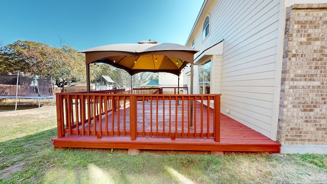 deck featuring a trampoline, a gazebo, and a lawn