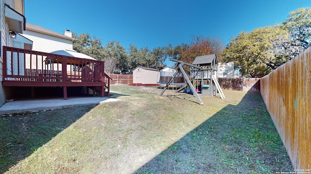 view of yard with a playground, a wooden deck, and a storage shed